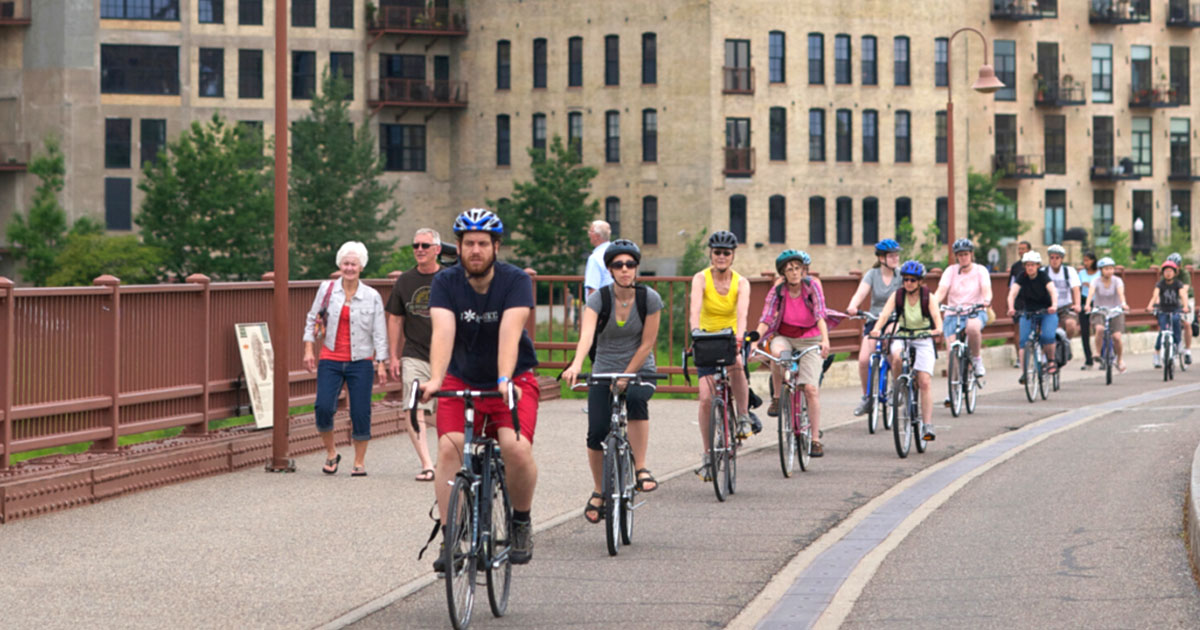A group of bike riders riding along the Stone Arch Bridge.