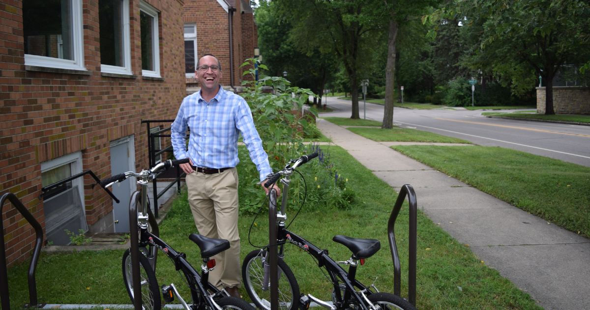 Person smiling in front of two parked bikes in Saint Paul