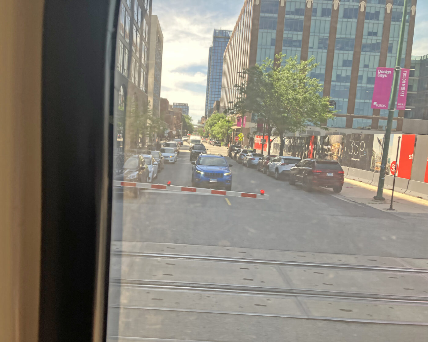 A downtown neighborhood with a line of cars waiting for the train to pass