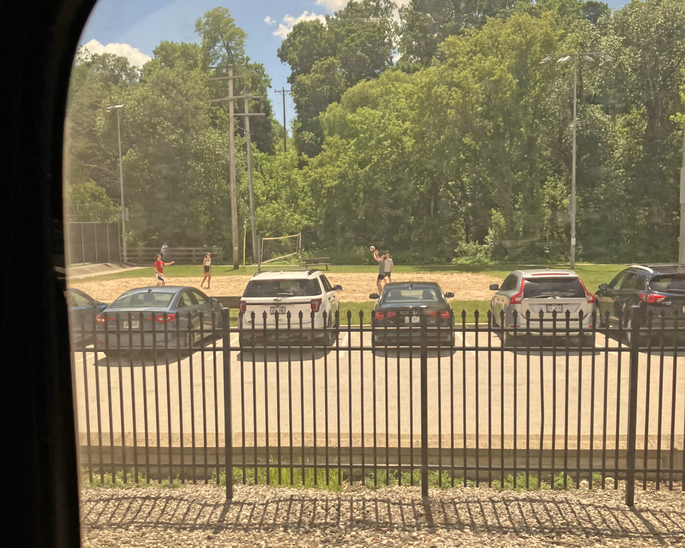 A park with a small group playing beach volleyball