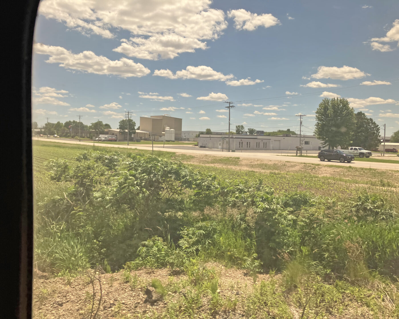 A blue sky with white clouds over low industrial buildings