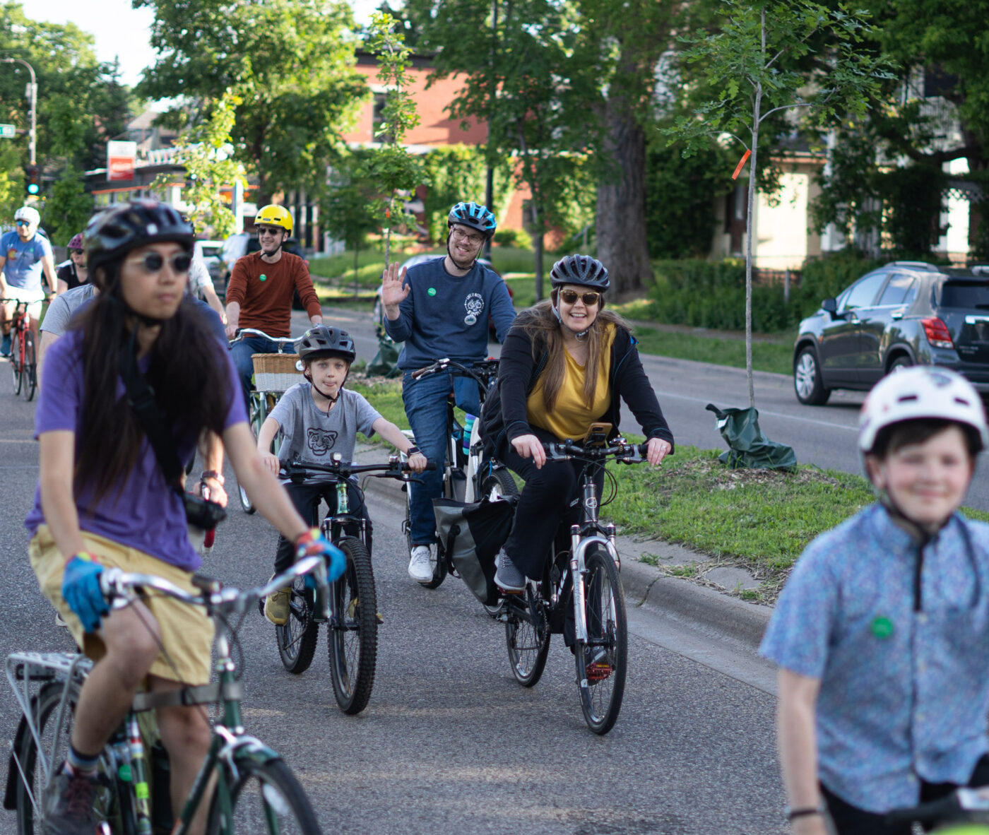 A group of bicyclists riding on the street, including several young people  