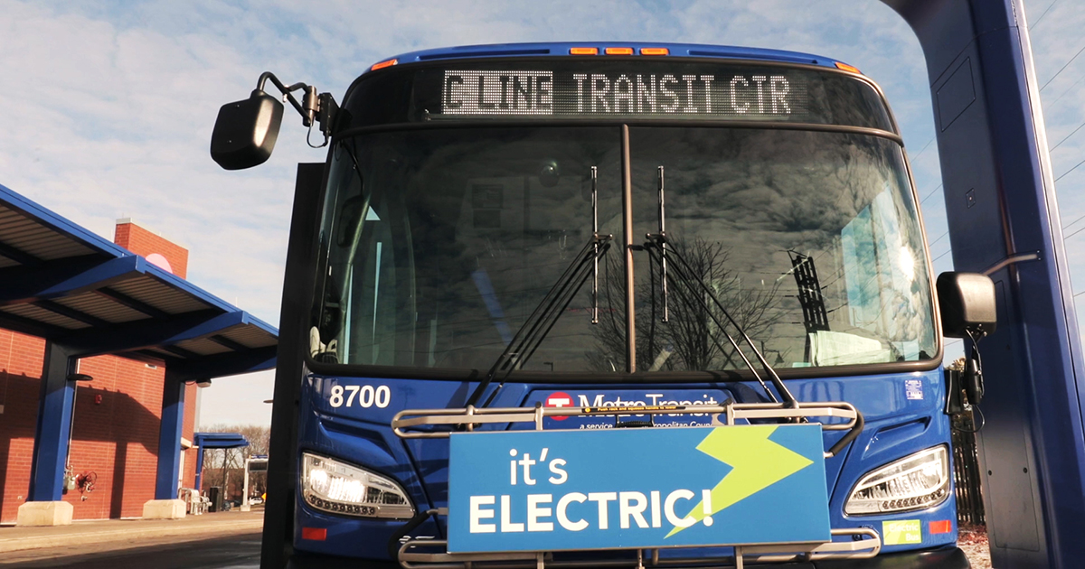 A Metro Transit C Line bus with a sign on the front that reads "It's Electric!"