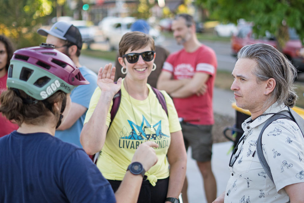 A female advocates wearing a bright yellow Livable Lyndale shirt waves at the camera at the rally 